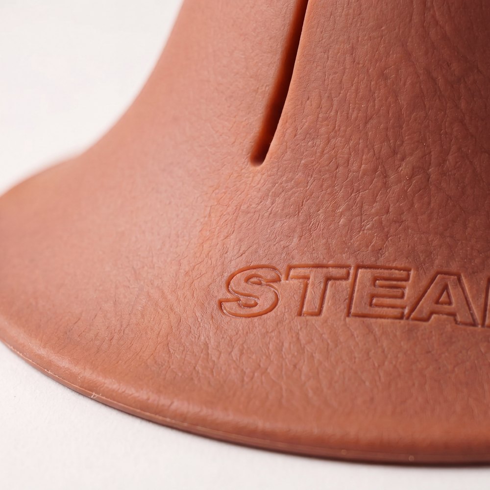 A macro photograph of the flared foot of a terracotta Steadi, showing the moulded STEADI mark.