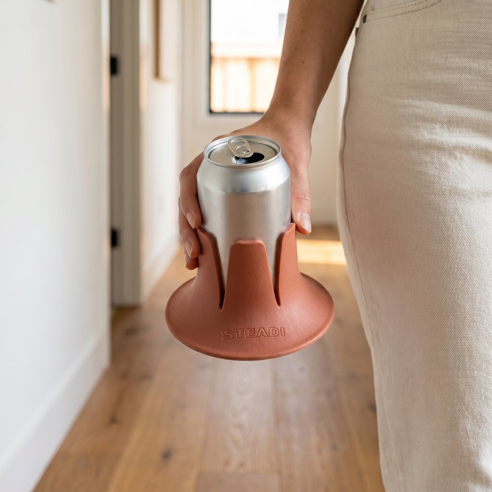 A hand carrying a can with a terracotta Steadi base still gripped on the bottom of it.